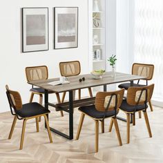 a dining room table with four chairs and a vase on the table in front of it