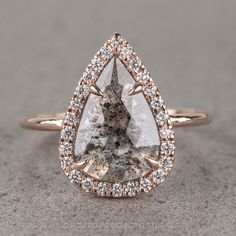 an engagement ring with a pear shaped diamond surrounded by small round diamonds on the band