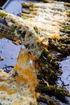 asparagus being grated with cheese on top of them in a baking dish