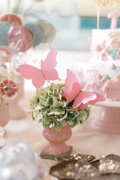 a pink vase filled with lots of flowers on top of a table covered in butterflies