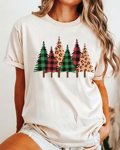 Imagine opening the Christmas gifts with your family on Christmas morning wearing this adorable Christmas Trees shirt. A perfect Country Xmas t-shirt. Charming plaid Christmas trees tee for a Holiday season. Merry and Bright tee for a woman. A cute Christmas gift for woman and a perfect outfit for the family Christmas card. Super soft and cozy. Unisex style and sizing.  HOW TO CHOOSE THE SIZE: Follow the measurements from the Size Chart included to determine your perfect size. Measurements are of the garments, not the person.  HOW TO MEASURE: Take a shirt you already own and love how it fits you, lay it flat on a floor and measure it across the chest and the length from the mid back down, compare to the Size Chart. *Hint: If you would like a more loose or oversize look, order a size or mor Trendy Christmas Shirts, Country Christmas Shirts, Vintage Christmas Shirt, Xmas Outfit, Retro Christmas Tree, Plaid Christmas Tree, Family Christmas Cards, Christmas Tree Shirt, Cute Christmas Gifts