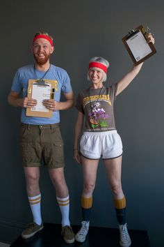 two people standing next to each other holding up papers and an award in front of them