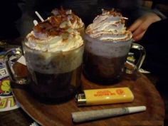 two beverages are sitting on a wooden tray