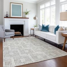 a living room with white couches and blue pillows on top of the area rug