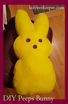 a yellow stuffed animal sitting on top of a wooden floor next to a brown bag