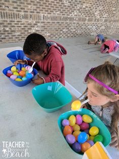 three children sitting at a table with buckets of candy