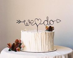 a white cake sitting on top of a table next to a couple's initials