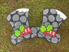 two decorated christmas mitts sitting on top of green grass covered in snowflakes