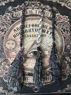 three tassels are hanging on a piece of fabric with writing and symbols in the background