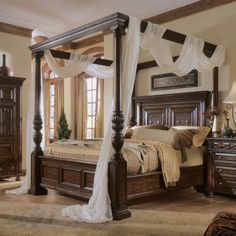 a bedroom with four post bed and white drapes