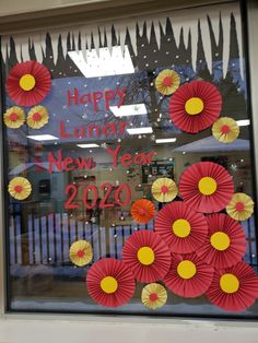 a window decorated with paper flowers and the words happy lunar new year written on it