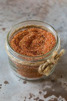 a glass jar filled with lots of different types of seasoning on top of a table