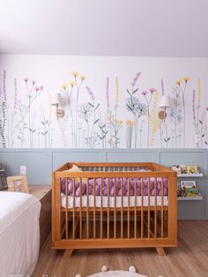 a baby's room with flowers painted on the wall and a crib in the foreground