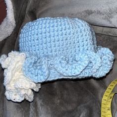 a blue crocheted hat with a white teddy bear laying on top of it