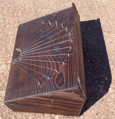 an old wooden box sitting on the ground with nails stuck in it's sides