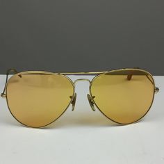 !950's Ray Ban Shooter, gold frame, bright yellow lens, Circa 1950's. BRIGHT yellow lens I think they called these Kalichrome. Feel free to ask me with any questions! sunglasses and case are in good vintage condition, light wear from storage to be expected and some pitting on the top of frame. Please ask questions before purchasing, all sales are final. Vintage Aviator Sunglasses With Gradient Lenses For Formal Events, Yellow Sunglasses With Mirrored Lenses For Formal Occasions, Formal Yellow Sunglasses With Mirrored Lenses, Vintage Aviator Sunglasses With Gradient Lenses For Formal Occasions, Vintage Gold Sunglasses For Formal Occasion, Gold Anti-reflective Sunglasses For Formal Occasions, Classic Gold Aviator Sunglasses With Mirrored Lenses, Vintage Summer Aviator Sunglasses, Formal Gold Anti-reflective Sunglasses