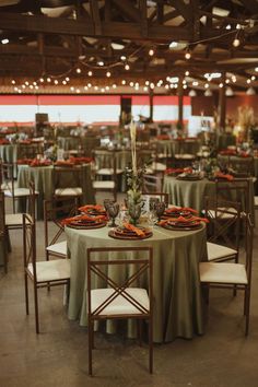 tables set up for an event with green tablecloths and white chairs, along with orange napkins