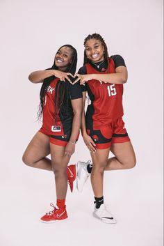 two women in red and black uniforms are posing for a photo with their arms around each other