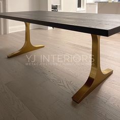 a large wooden table with gold legs in an empty living room or dining room area