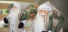 two santa figurines are holding plants in their hands