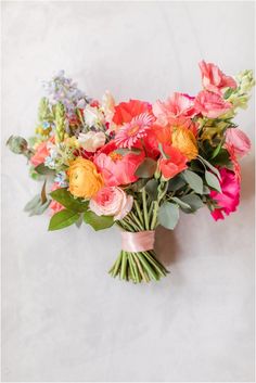 a bunch of flowers that are sitting on a table in front of a white wall