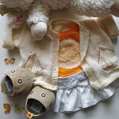 a teddy bear is laying next to some clothes and shoes on a table with butterflies around it