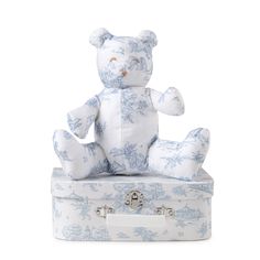 a blue and white teddy bear sitting on top of a suitcase