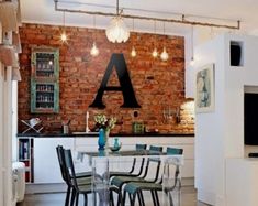 a dining room table and chairs in front of a brick wall with lights hanging from it