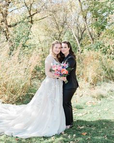 the bride and groom pose for a photo in front of some tall grass with trees behind them