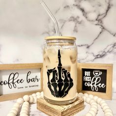 a mason jar filled with liquid and topped with a straw in front of a sign that says coffee bar