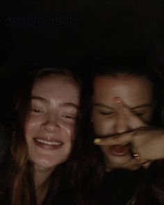 two young women are smiling together in the dark