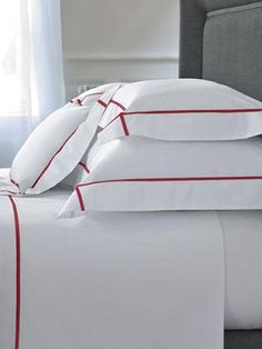 a bed with white sheets and red trimmings