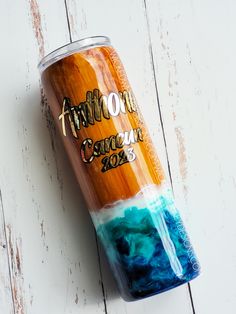 an orange, blue and white coffee cup sitting on top of a wooden table next to a wall