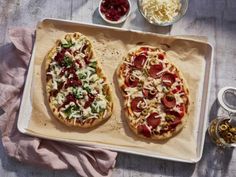 two pizzas sitting on top of a pan covered in toppings