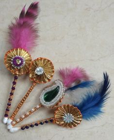 three different colored feathers with jewels and pearls on them are laying next to each other