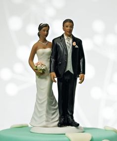 a bride and groom figurine standing next to each other on a white background