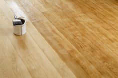 a wooden floor with a paint roller on it and a can in the middle next to it