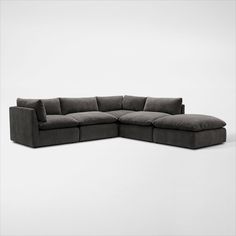 a large sectional couch with pillows on the bottom and back ends, in dark grey fabric