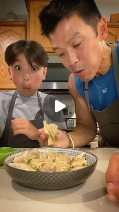 a father and son are preparing food in the kitchen while looking at something on the plate