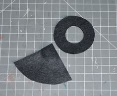 a pair of black felt pieces on a cutting board with a ruler and scissors next to them