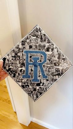 a person holding up a graduation cap with the letter r on it in front of a door