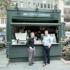 two men standing in front of a coffee shop