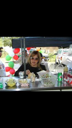 a woman sitting at a table with food in front of her and balloons behind her