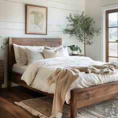 a bed with white linens and pillows in a bedroom next to a plant on the wall