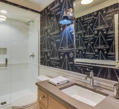 a bathroom with a black and white wallpaper that has boats drawn on the walls