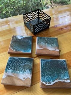 four ceramic coasters sitting on top of a wooden table