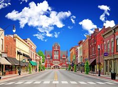 an empty city street with buildings on both sides and clouds in the sky above it