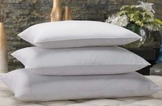 three pillows stacked on top of each other in front of a brick wall and vase