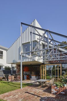 an outdoor patio with tables and chairs under a metal roof over looking the back yard