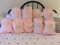 six pink bags with monogrammed initials on them sitting on top of a bed